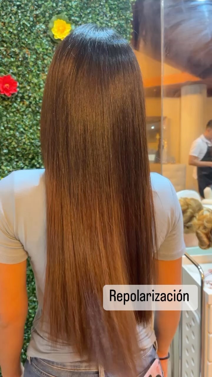 Cabello largo con repolarización frente al muro verde con flores del salón